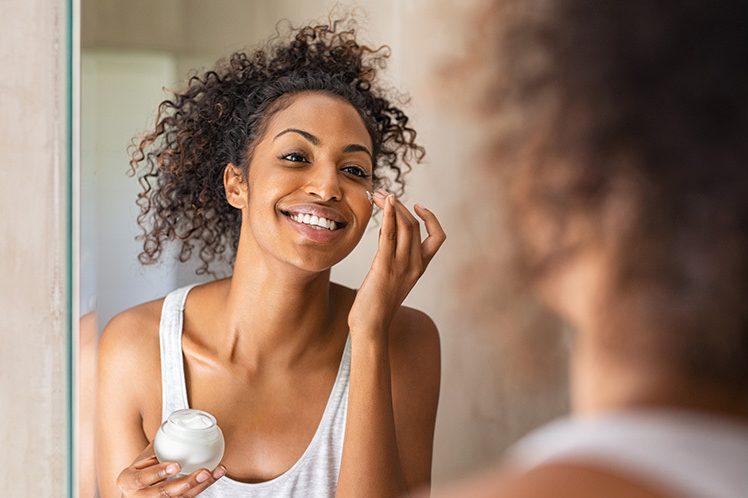 Woman of color applies skin care