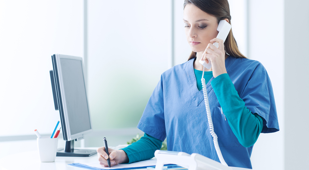 nurse on the phone writing on a piece of paper